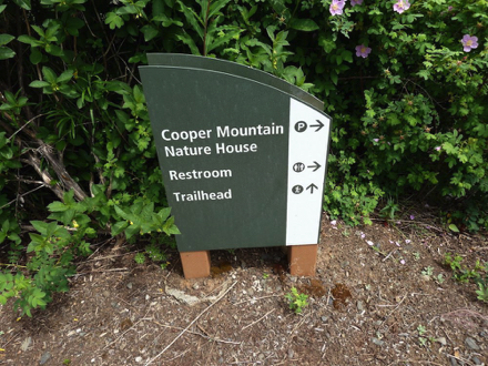 Directional sign that points to Cooper Mountain Nature House, restroom and trailhead